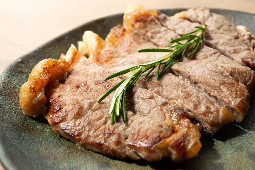 delicioso rosbife, em um prato preto e superfície de madeira, com um raminho de tomilho por cima