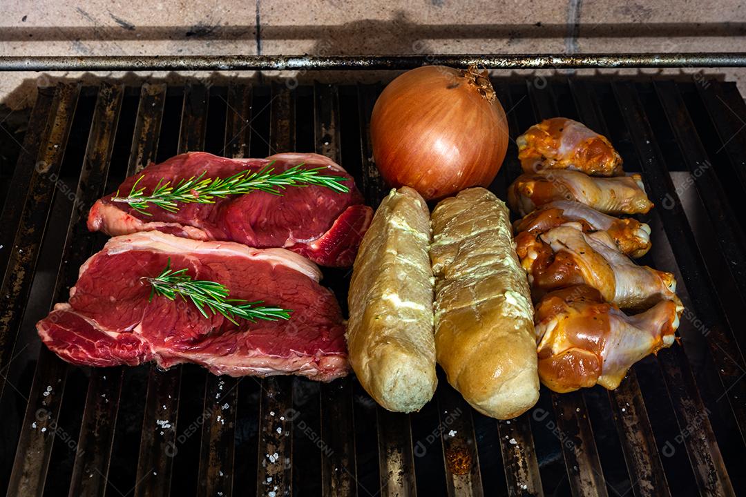 grelha com itens tradicionais do churrasco brasileiro, bife do lombo, pão de alho. coxinha de frango, cebola.