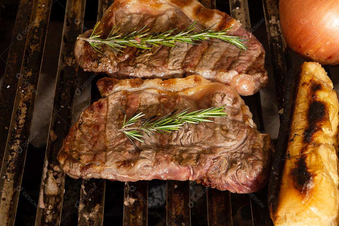 grelha com itens tradicionais do churrasco brasileiro, bife do lombo, pão de alho. coxinha de frango, cebola.