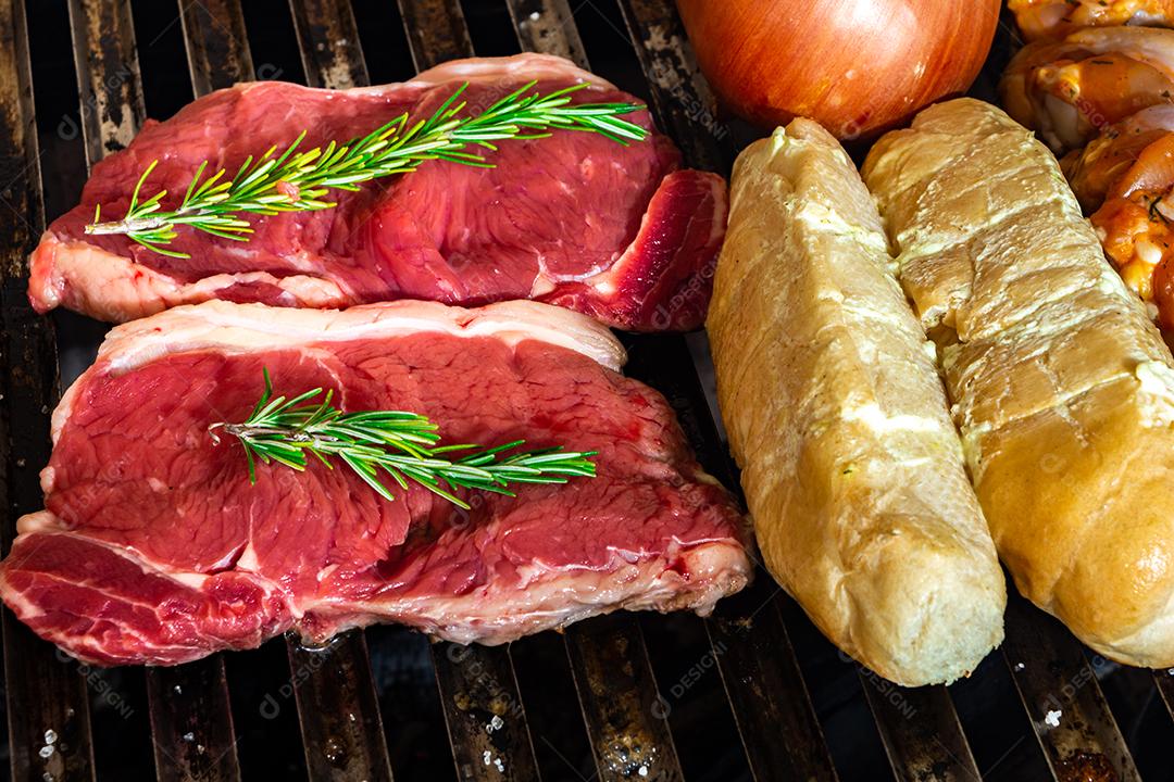 grelha com itens tradicionais do churrasco brasileiro, bife do lombo, pão de alho. coxinha de frango, cebola.