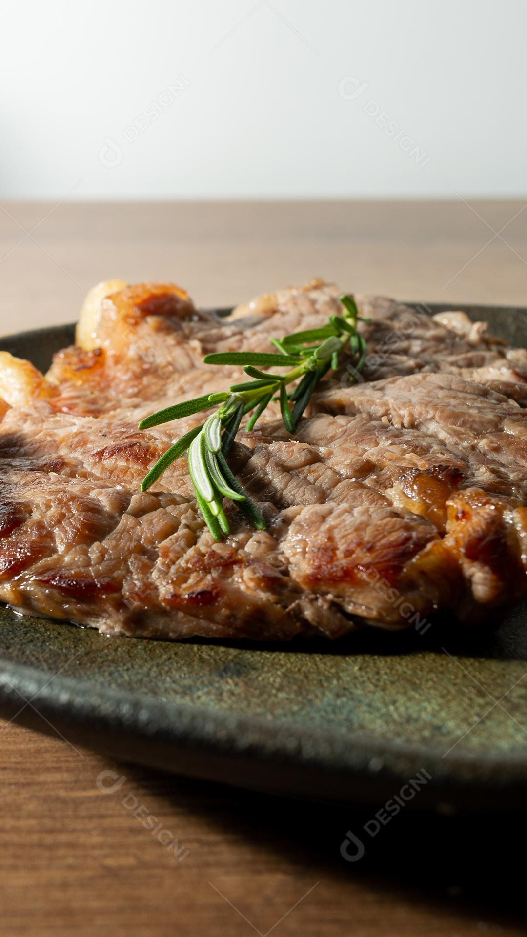 delicioso rosbife, em um prato preto e superfície de madeira, com um raminho de tomilho por cima