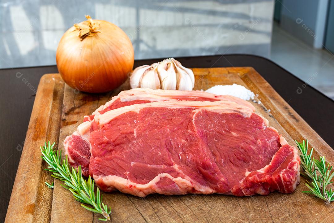 carne vermelha crua, bife do lombo com gordura em uma tábua junto com tomilho. temperos naturais prontos para o churrasco no quintal da família