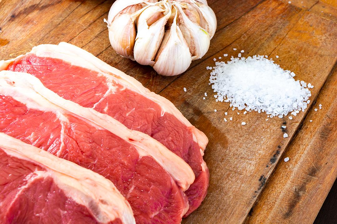 carne vermelha crua, bife do lombo com gordura em uma tábua junto com tomilho. temperos naturais prontos para o churrasco no quintal da família