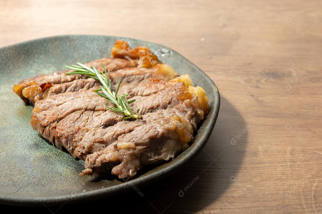 delicioso rosbife, em um prato preto e superfície de madeira, com um raminho de tomilho por cima