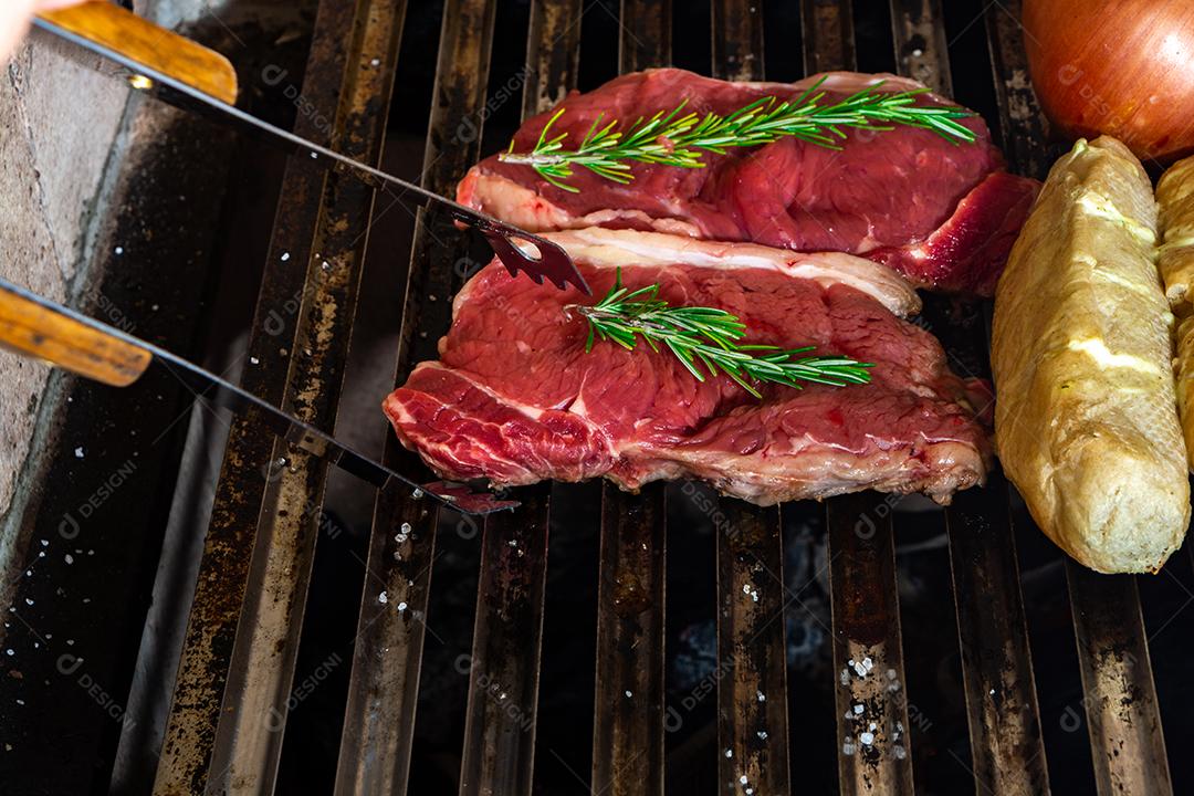 grelha com itens tradicionais do churrasco brasileiro, bife do lombo, pão de alho. coxinha de frango, cebola.