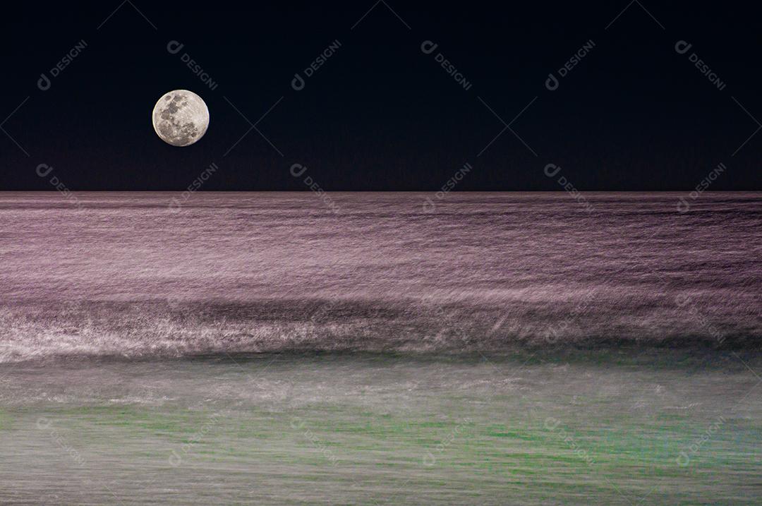 Lua cheia refletindo no mar em um dia de ressaca em uma praia brasileira.