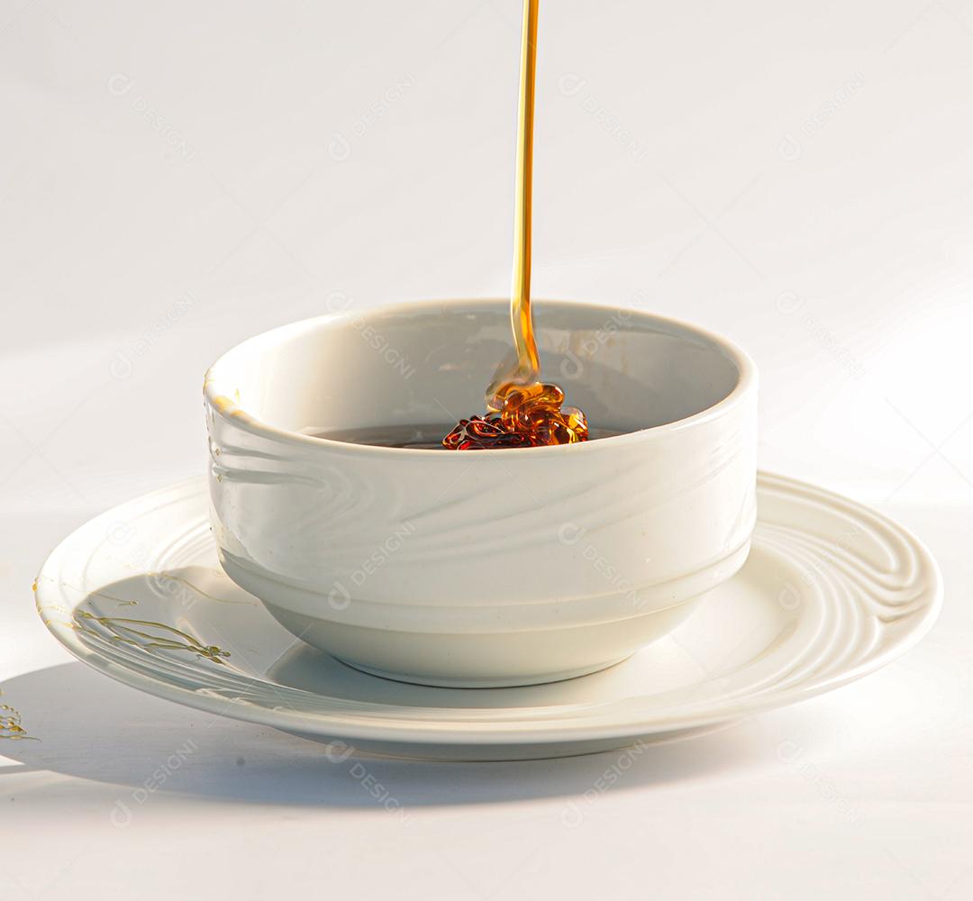 Mel sendo derramado em um pote branco, produzido na hora