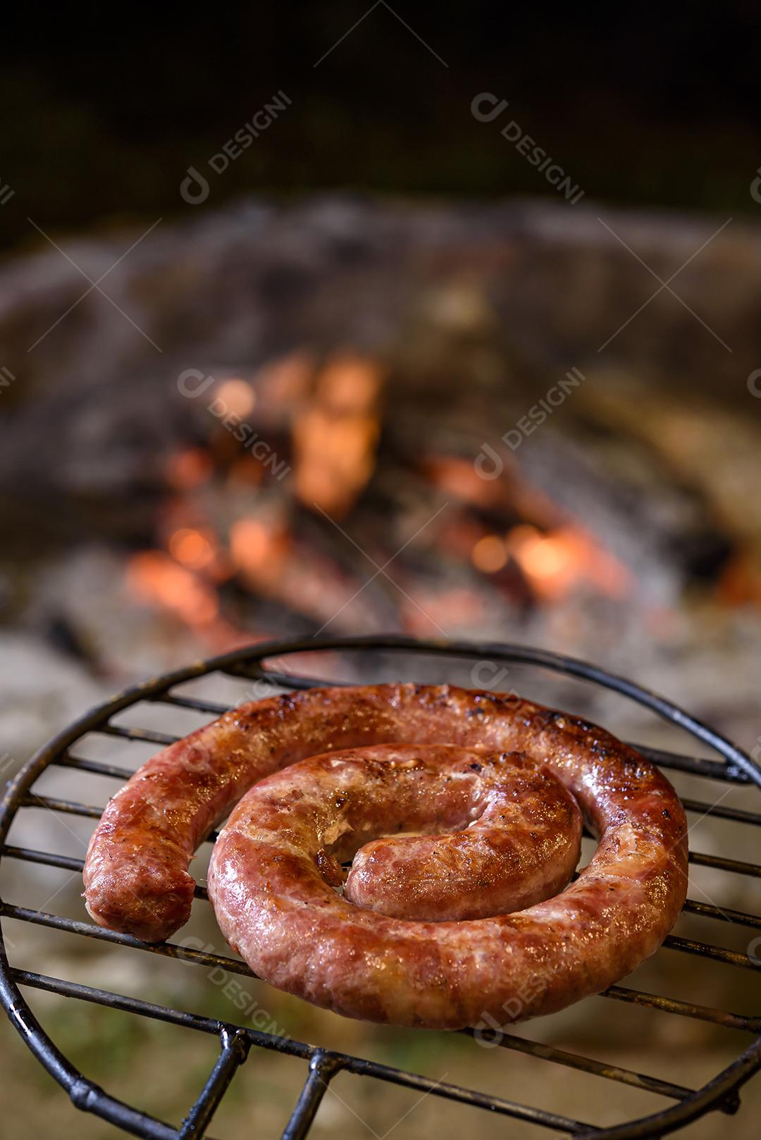 Salsicha caseira brasileira assando na grelha sobre brasas.
