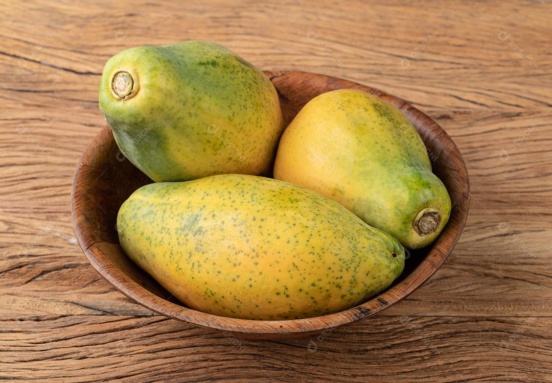 Mamão em uma tigela sobre a mesa de madeira.