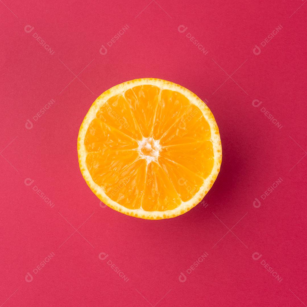 Metade laranja isolada sobre plano de fundo texturizado vermelho.