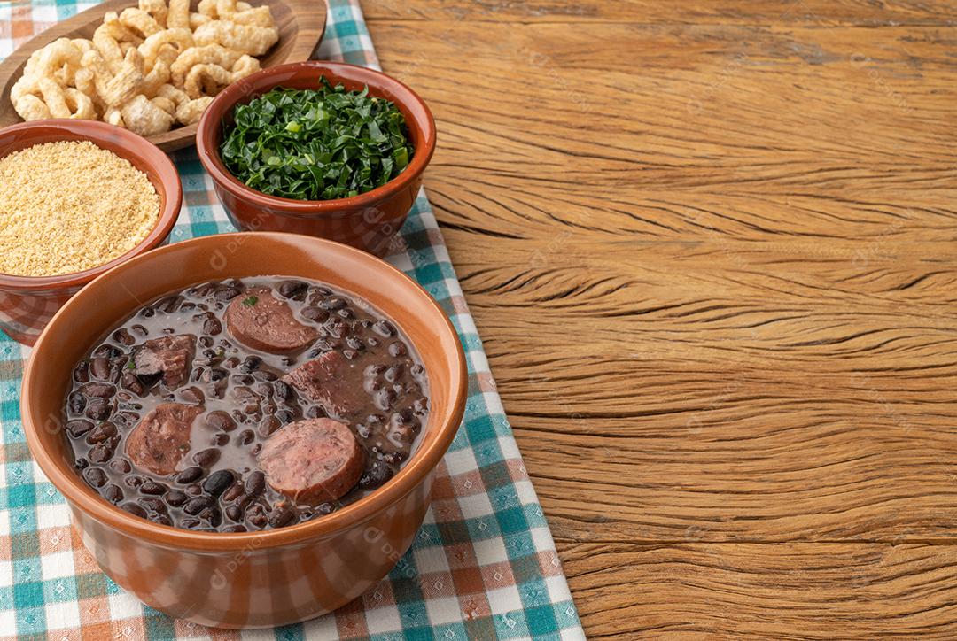 Feijoada tradicional brasileira em uma tigela sobre a mesa de madeira.