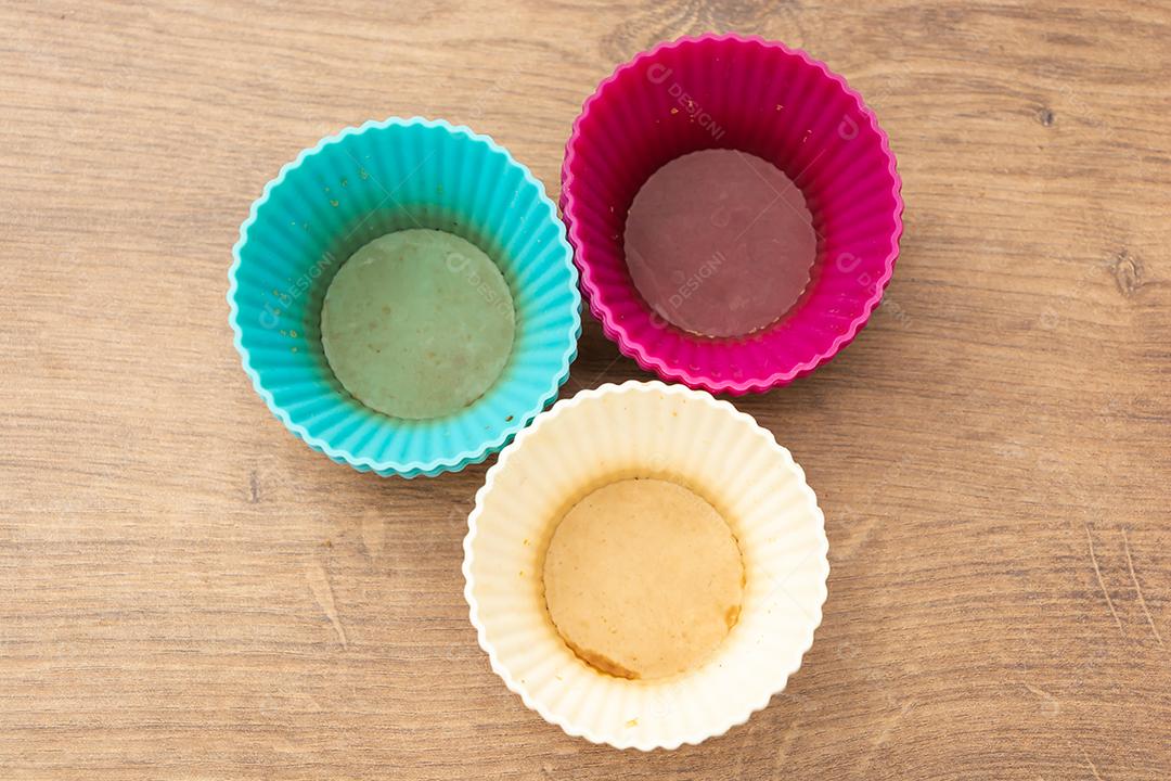 grupo de moldes de silicone coloridos para cupcake, nas cores branco, roxo e azul