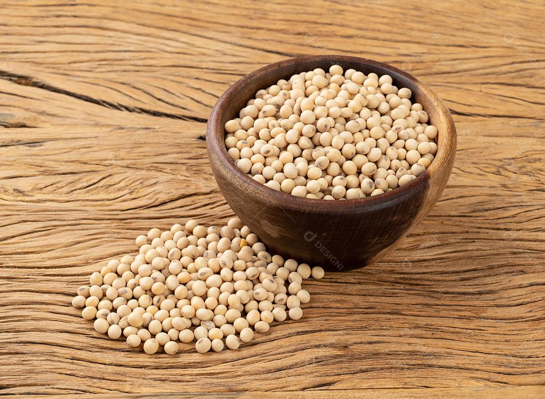 Grãos de soja crus em uma tigela sobre a mesa de madeira.