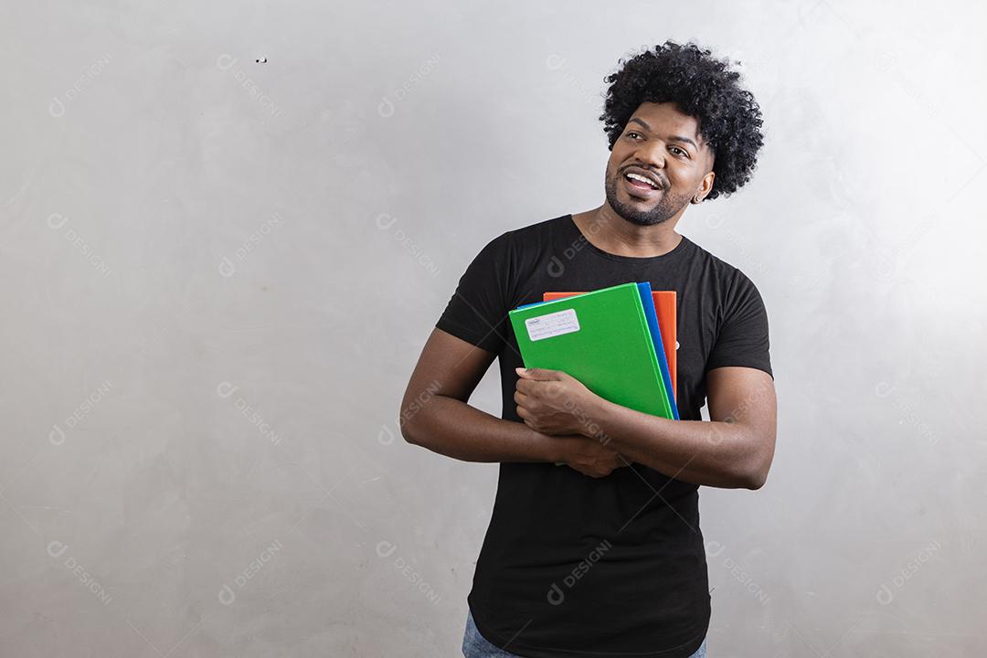 jovem estudante negro com livros e cadernos no fundo