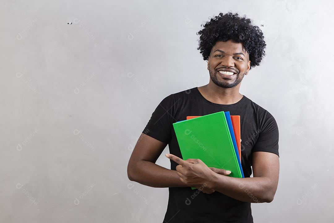 jovem estudante negro com livros e cadernos no fundo
