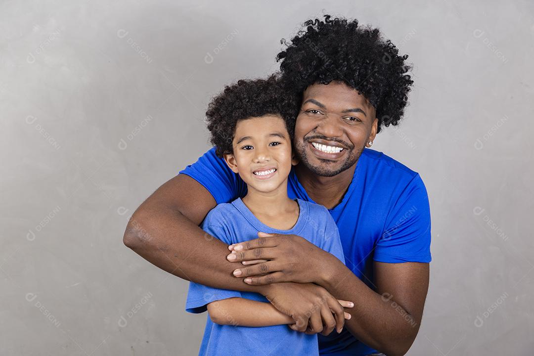 filho sentado no ombro do pai em fundo cinza. Feliz afro pai e filho