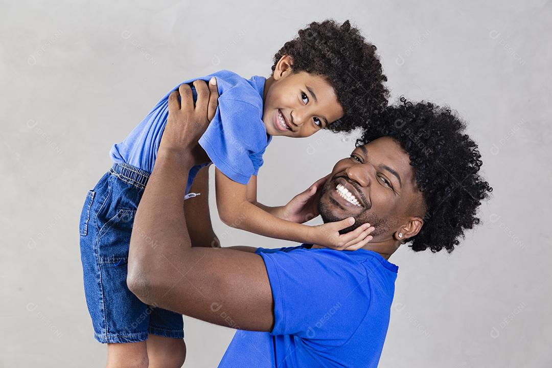 Afro pai e filho negro sobre fundo cinza sorrindo e feliz. papai afro no dia dos pais. dia dos pais em agosto