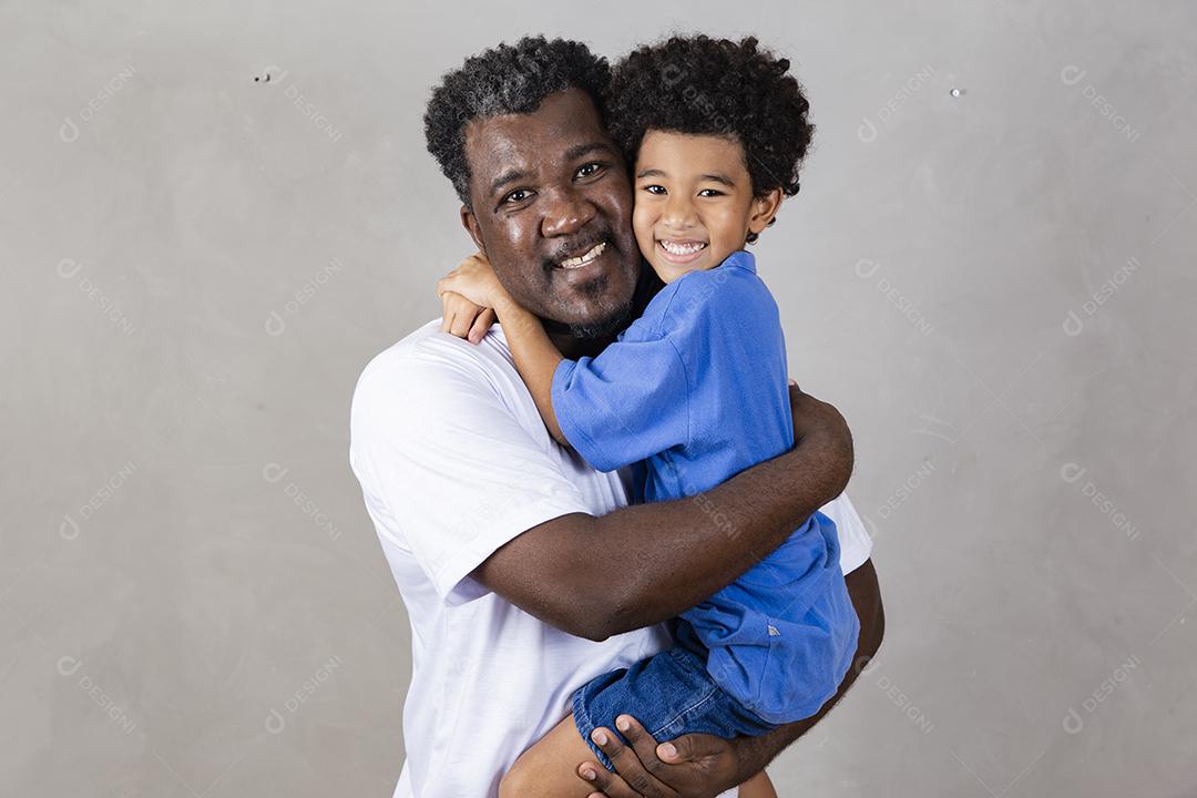 Afro pai e filho negro sobre fundo cinza sorrindo e feliz. papai afro no dia dos pais. dia dos pais em agosto