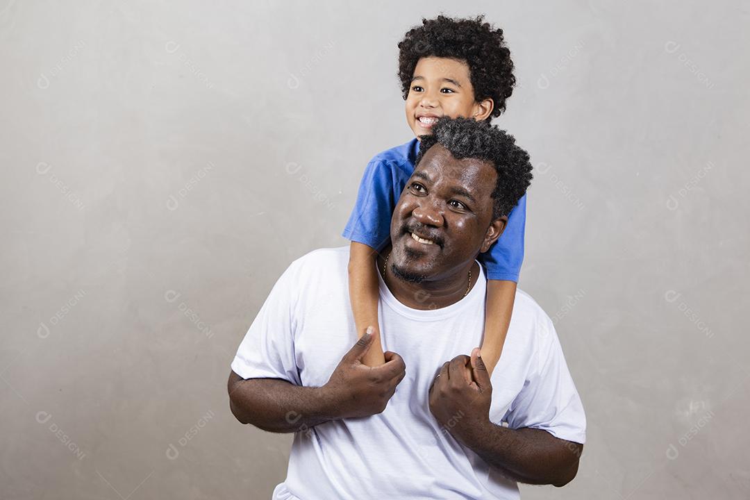 Afro pai e filho negro sobre fundo cinza sorrindo e feliz. papai afro no dia dos pais. dia dos pais em agosto