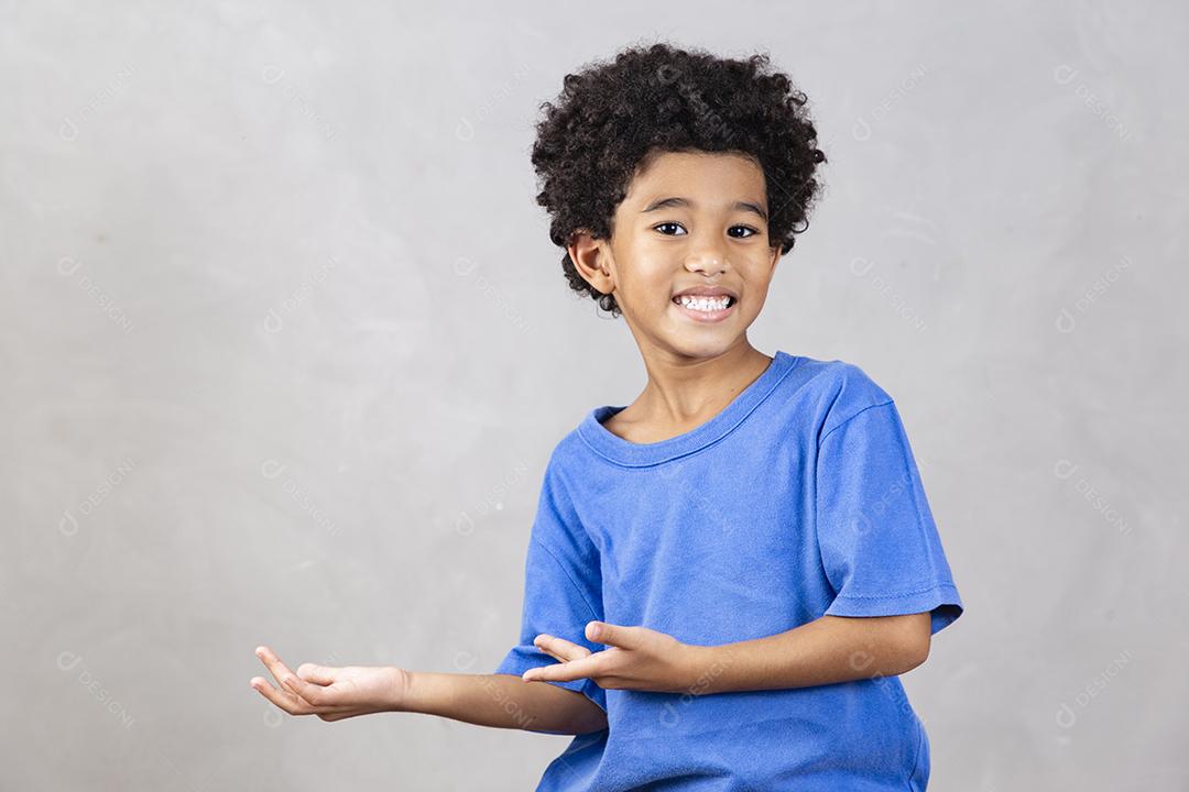 adorável menino afro com braços cruzados sorrindo em fundo cinza