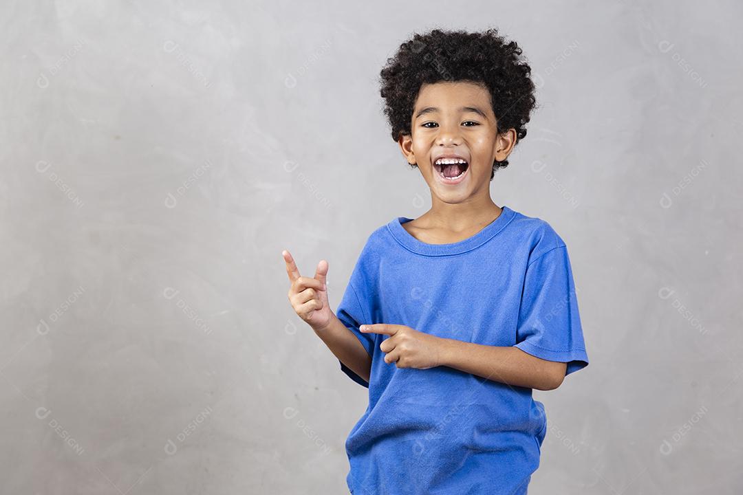 adorável menino afro com braços cruzados sorrindo em fundo cinza