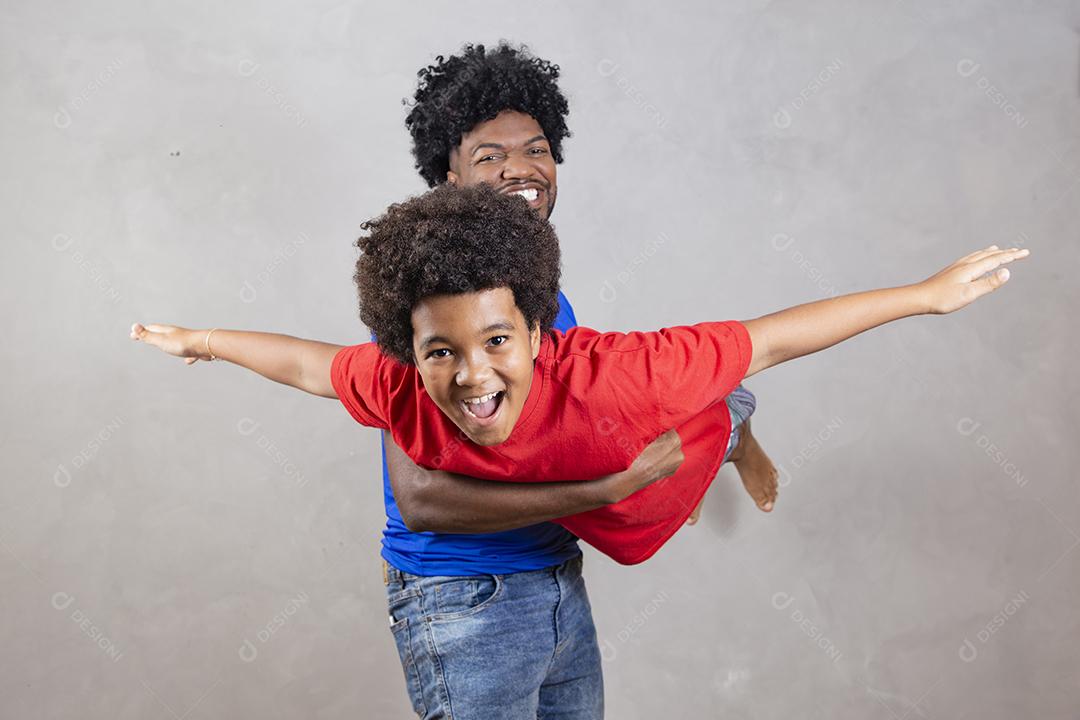 Afro pai e filho negro sobre fundo cinza sorrindo e feliz. papai afro no dia dos pais. dia dos pais em agosto