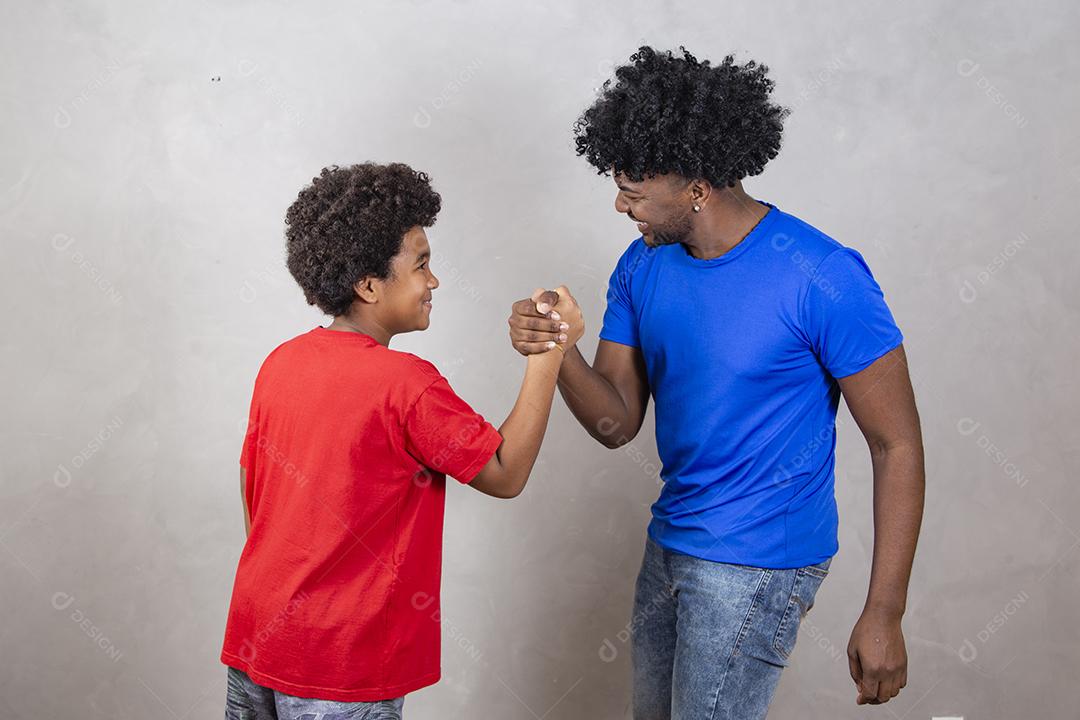 Afro pai e filho negro sobre fundo cinza sorrindo e feliz. papai afro no dia dos pais. dia dos pais em agosto