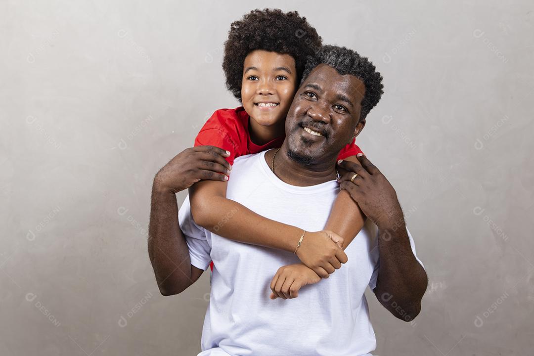 Filho afro abraçando seu pai em fundo neutro