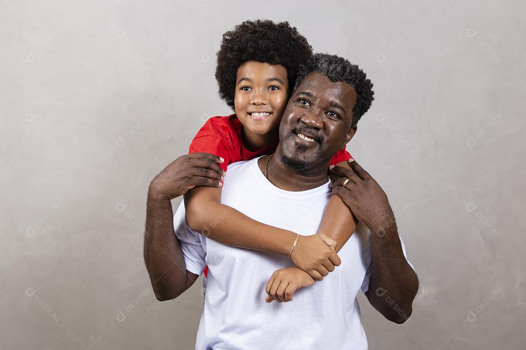 Filho afro abraçando seu pai em fundo neutro