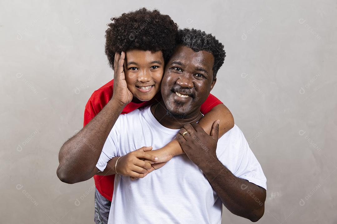 Filho afro abraçando seu pai em fundo neutro