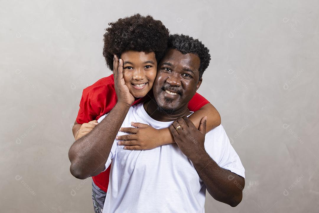 Filho afro abraçando seu pai em fundo neutro