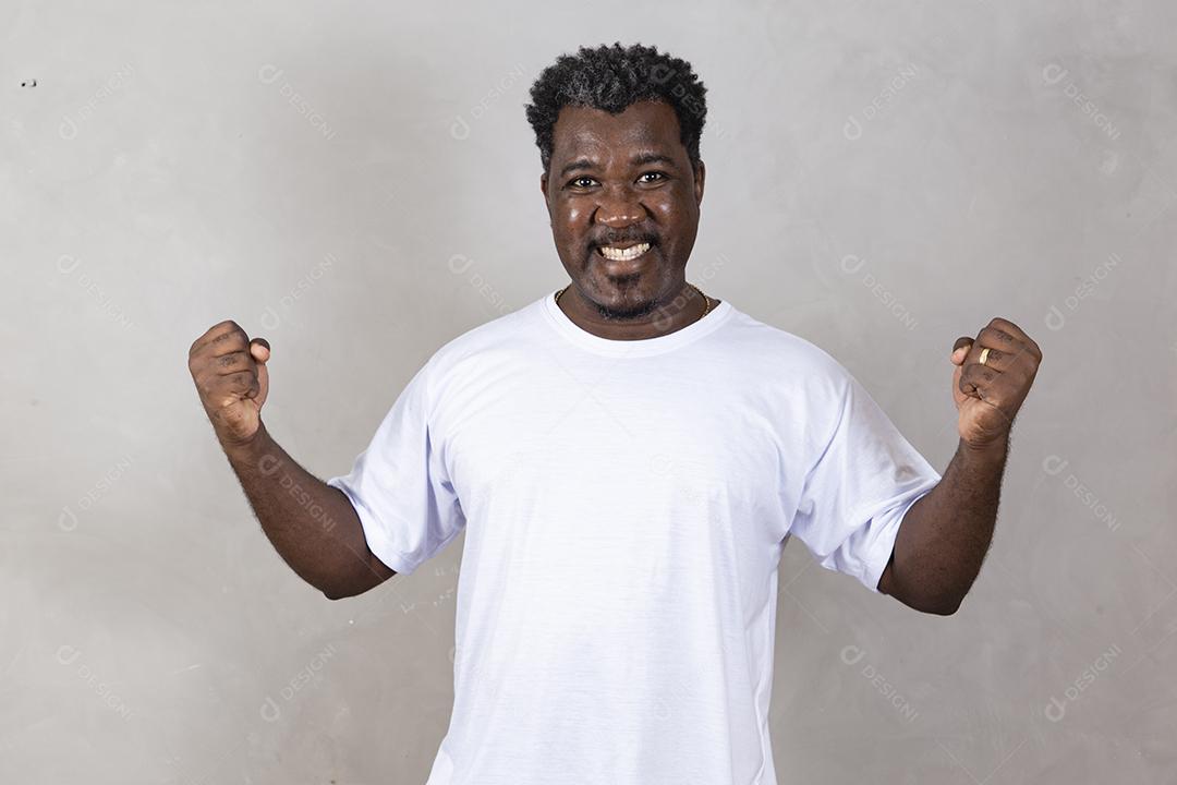 Homem afro emocional gritando punhos trêmulos sobre o fundo cinza do estúdio olhando para a câmera