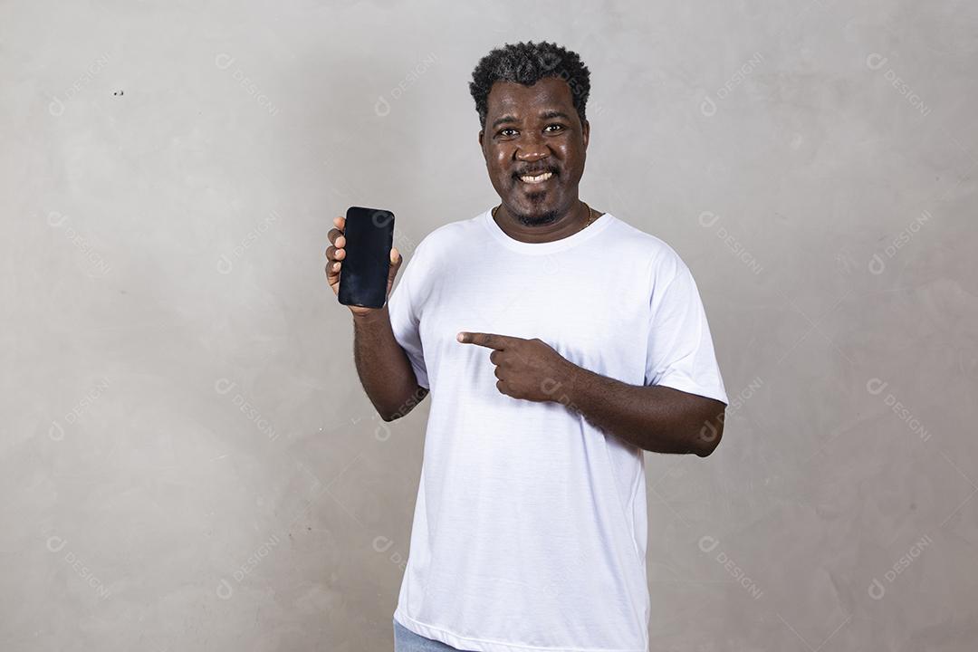 Publicidade em aplicativos móveis. Animado homem afro bonito mostrando apontando para a tela branca vazia do smartphone