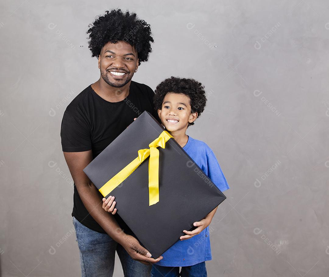 afro pai e filho em fundo neutro com presente
