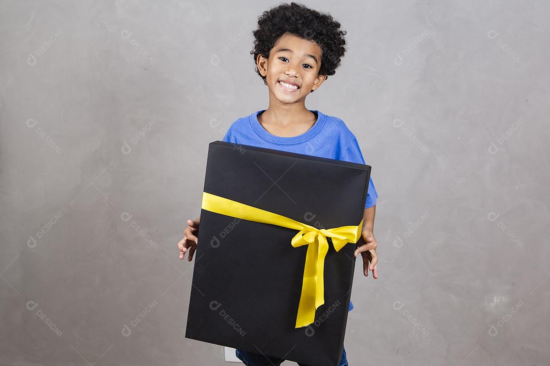 adorável menino afro segurando uma grande caixa de presente