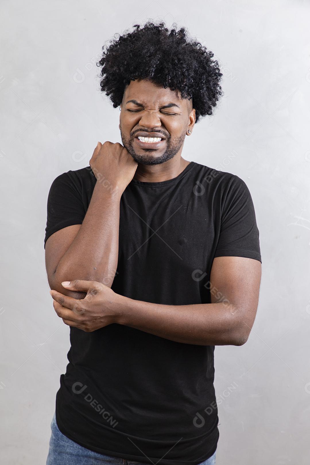 Jovem afro com dor aguda na articulação do cotovelo, fundo branco