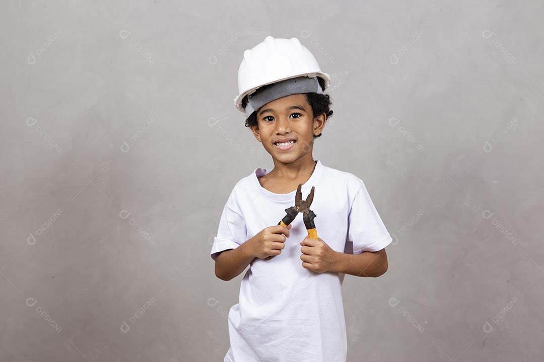 adorável garotinho vestido como um construtor segurando uma ferramenta de alicate