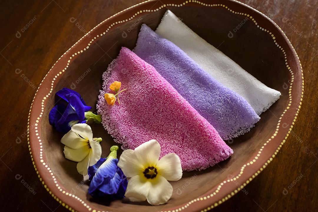 Tapioca. Tapiocas brasileiras coloridas servidas em tigelas de barro com flores silvestres no café da manhã.