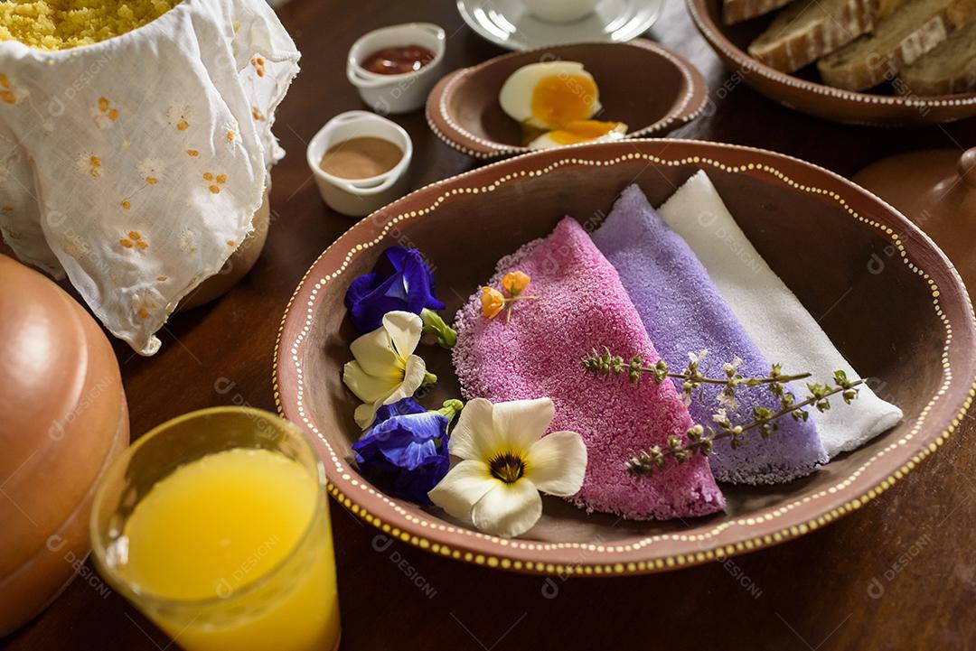 Tapioca. Tapiocas brasileiras coloridas servidas em tigelas de barro com flores silvestres no café da manhã.