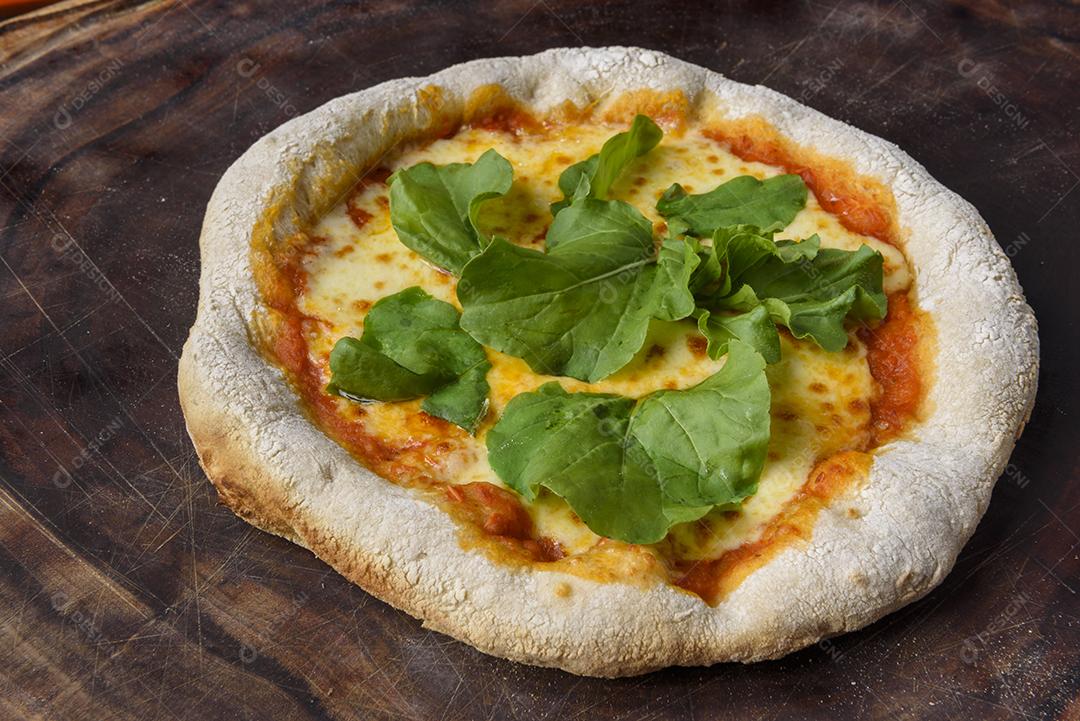 Pizza. Pizza de queijo caseiro com rúcula sobre madeira.