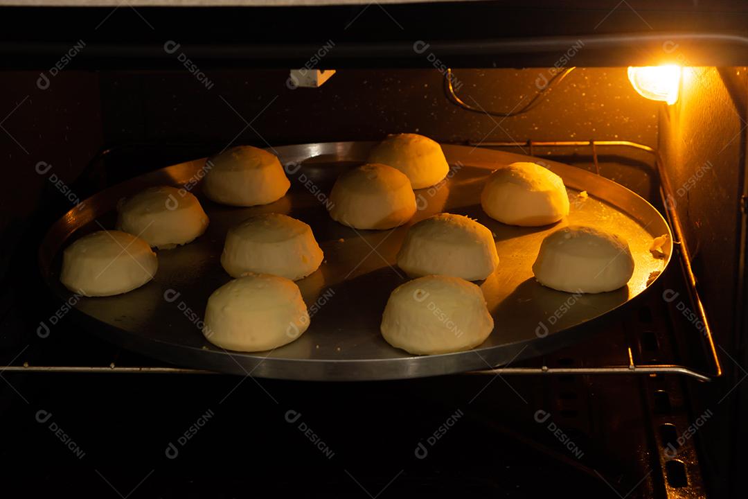 pão de queijo sendo assado em um forno em uma assadeira de metal