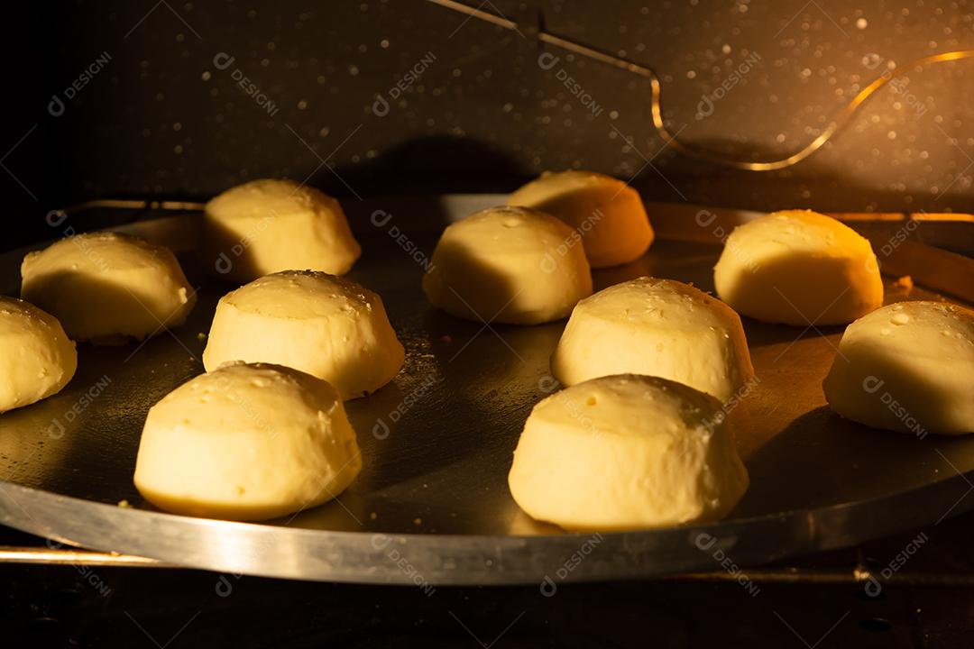 pão de queijo sendo assado em um forno em uma assadeira de metal