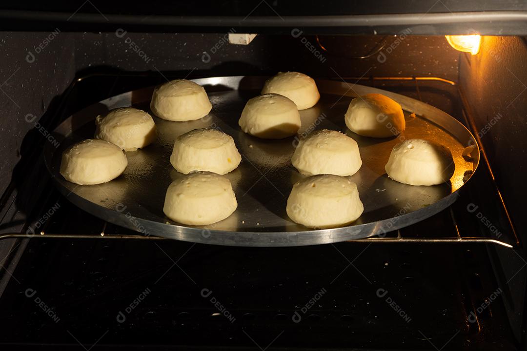 pão de queijo sendo assado em um forno em uma assadeira de metal