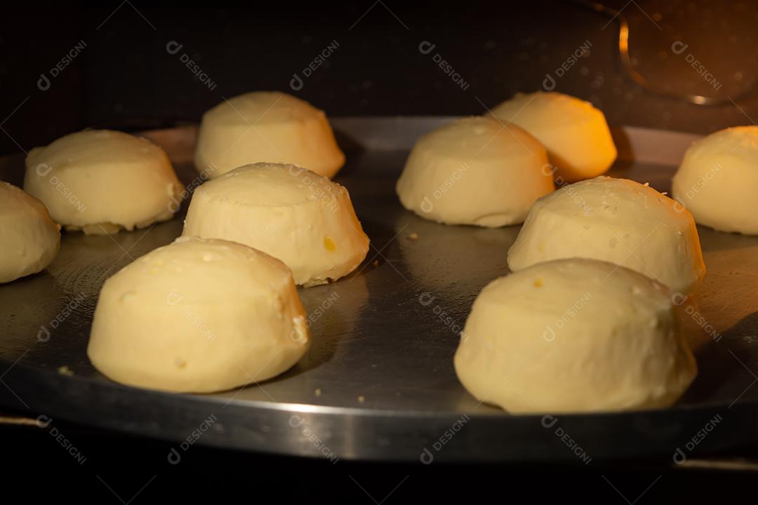 pão de queijo sendo assado em um forno em uma assadeira de metal