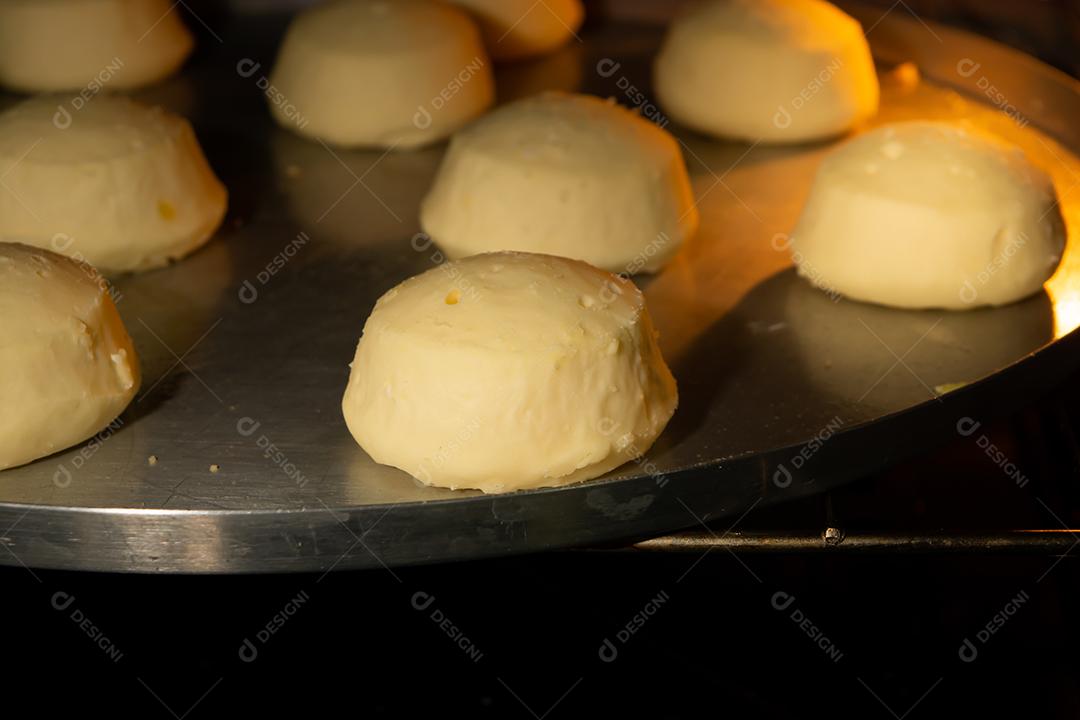 pão de queijo sendo assado em um forno em uma assadeira de metal