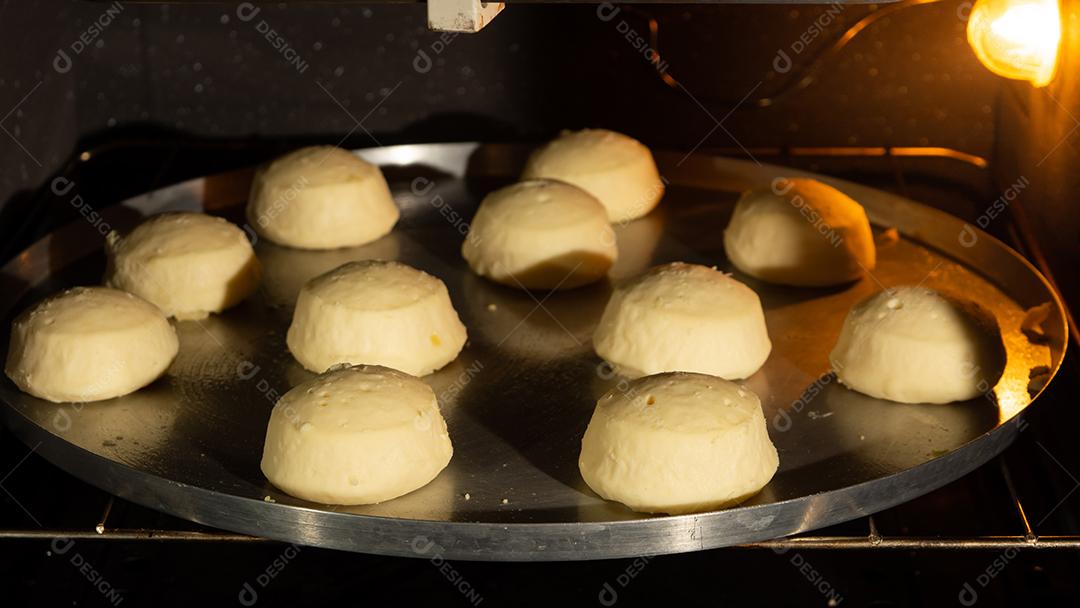 pão de queijo sendo assado em um forno em uma assadeira de metal