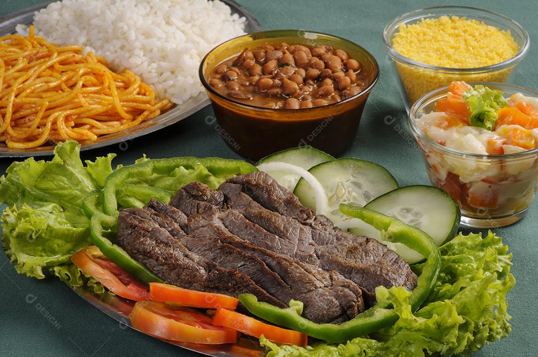Carne de sol, prato popular do nordeste brasileiro, servida com salada verde, feijão, arroz, macarrão e farofa.