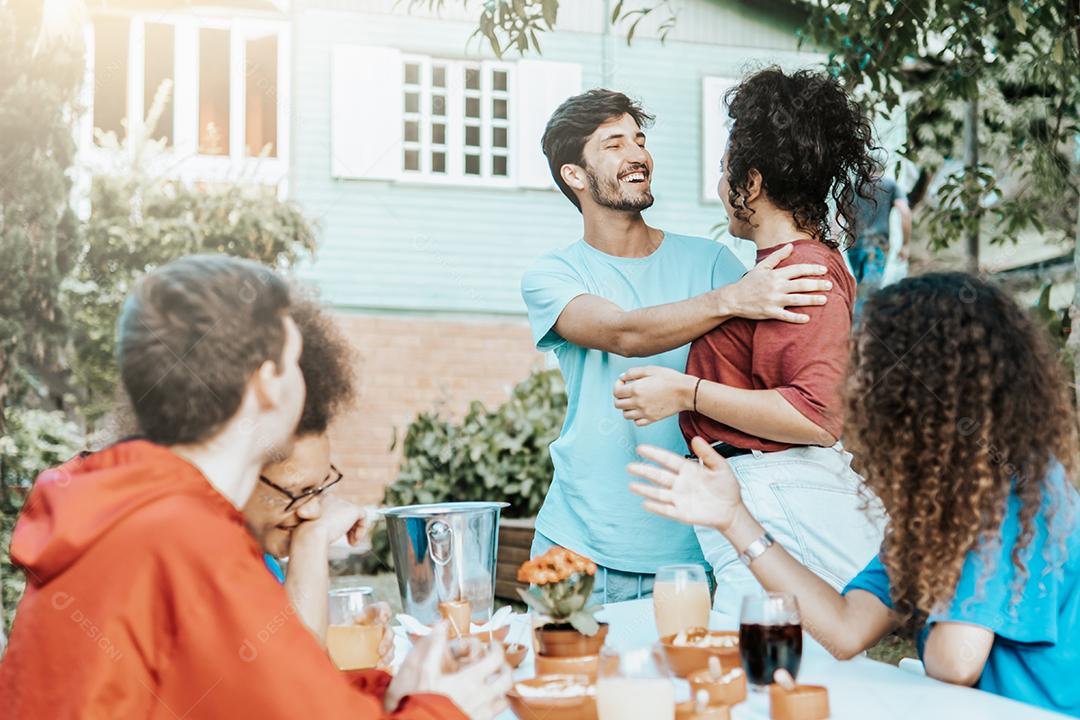 Reunião de amigos em uma festa no quintal - Encontro de amigos felizes comendo e bebendo - Foco no homem barbudo