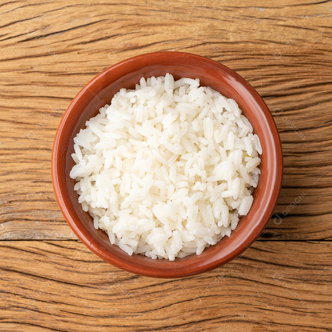 Arroz branco cozido em uma tigela sobre a mesa de madeira.