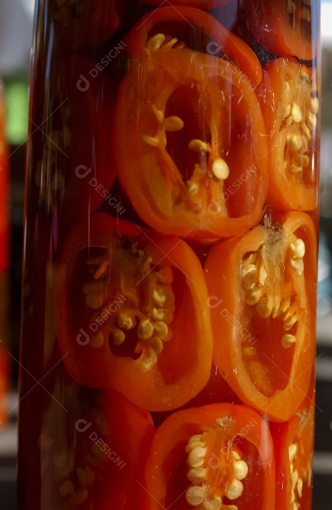 Pimenta artesanal em garrafas de vidro à venda em uma feira popular no Brasil.